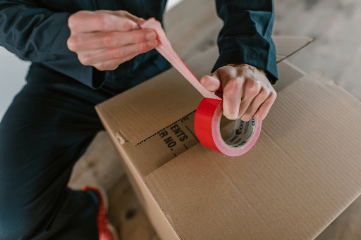 Moving crew member using tape to secure a packed box for a home remova