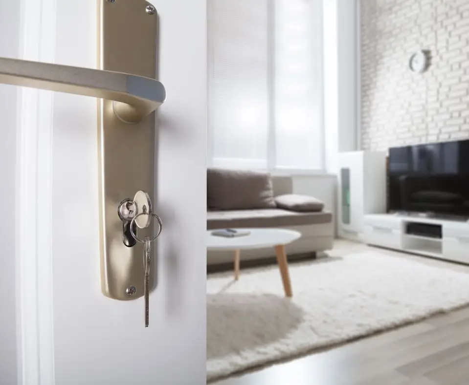 Close-up Of Door Handle With Inserted Key In The Keyhole And House