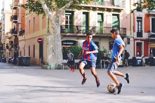 an image of two boys playing football in Barcelona town centre, after school