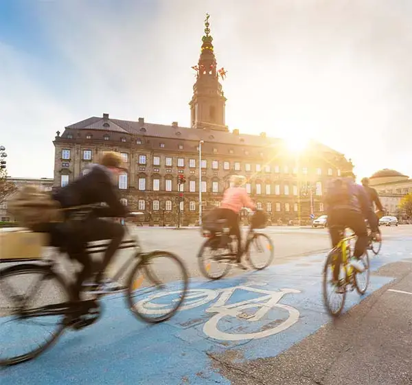 Blurred people going by bike in Copenhagen, with Christiansborg palace on background