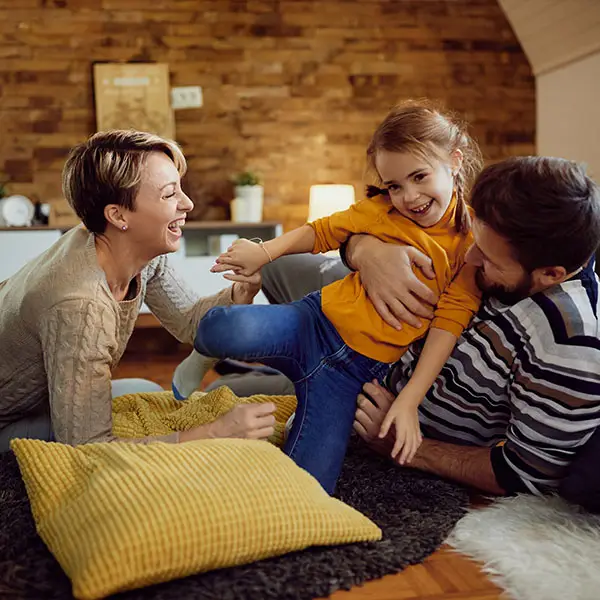 Happy small girl having fun with her parents at home