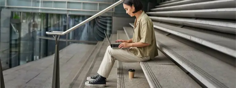 Digital Nomad asian woman with laptop sits stairs outside building
