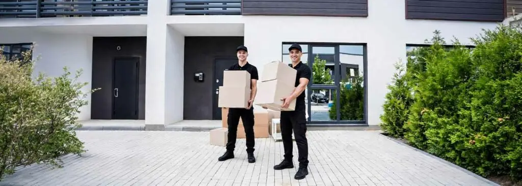 Two International Removals crew with packing boxes outside a house