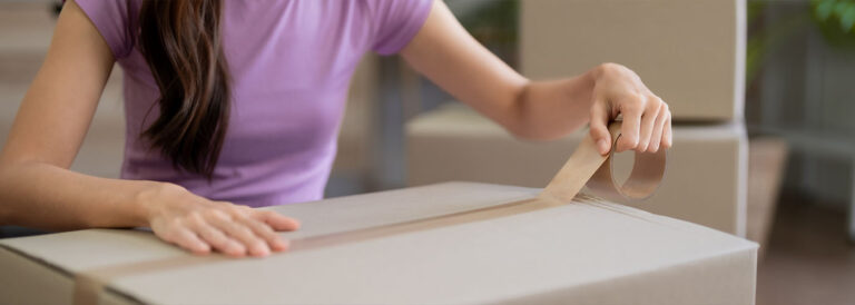 Asian woman packing boxes with tape for moving to new house apartment