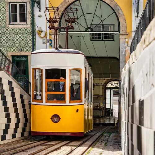 Yellow elevator going up the slope of one of the typical neighborhoods in the city of lisbon in portugal - bica elevator